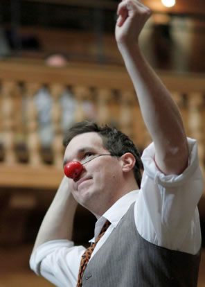 John Harrell as Feste wearing a red nose and dancing