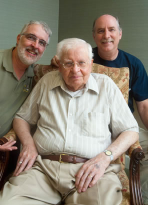 Portrait of my dad sitting in a chair with me on one side and my brother, John, on the other.