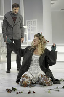 Laertes looks down on the distracted Ophelia, kneeling on the ground amid her flowers