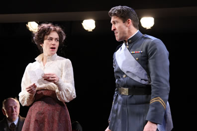 Beatrice holds a letter and looks amusingly at Benedick in uniform, who looks pained at the revelation in the letter