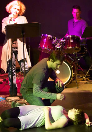 Lucrece lies sleeping on the floor with Tarquin bent over her, the narrator standing and the drummer behind his kit in the background